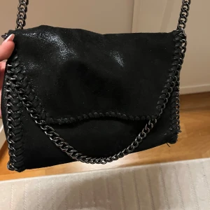 Svart väska med fack och kedja - Denna väskan är perfekt storlek för att ha varje dag. Bra material och kedjan håller färgen🩷