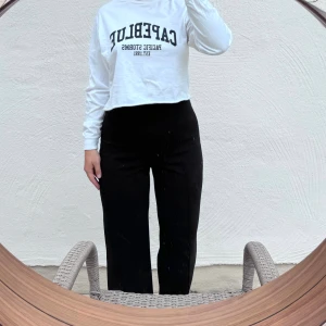 Vit croppad tröja från Capeblue - Säljer en superfin vit croppad tröja från Capeblue med tryck 'Pacific Storms Est. 1991' i marinblått. Tröjan har långa ärmar och är perfekt för en avslappnad stil. 