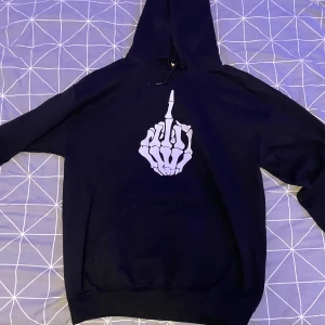 Svart hoodie med skelettmotiv - Säljer en svart hoodie med ett coolt skelettmotiv på framsidan. Den har en stor ficka fram och en bekväm huva. Rätt så använd men märks inte. 