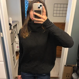 Svart stickad tröja från 157 - Säljer en mysig svart stickad tröja från lager 157. Den har en hög krage och långa ärmar, perfekt för kyliga dagar. Tröjan är i storlek S och passar bra till både jeans och kjol. Perfekt för höst och vinter!