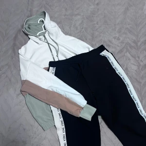 Flerfärgad SET - En supercool flerfärgad SET från NewYorker. Den har en avslappnad passform med en kombination av vitt, beige och grönt. Hoodien har en stor ficka framtill och justerbar huva med snören.