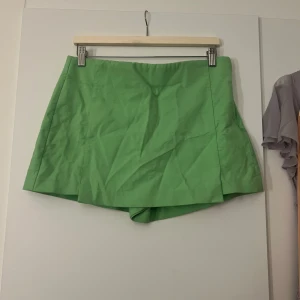 Grön kortkjol - Säljer en superfin grön kortkjol som är perfekt för sommaren! Kjolen har en enkel och stilren design, vilket gör den lätt att matcha med olika toppar. Den är i ett mjukt och bekvämt material, perfekt för varma dagar. Passar både till vardags och festliga tillfällen. 🌿