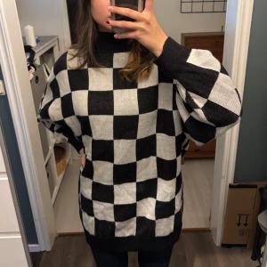 Svartvit rutig tröja från Divided - Säljer en supercool svartvit rutig tröja från H&M. Den är stickad och har en oversized passform som är perfekt för både höst och vinter. Tröjan har långa ärmar och en hög krage som håller dig varm och mysig. Perfekt för en avslappnad stil eller at