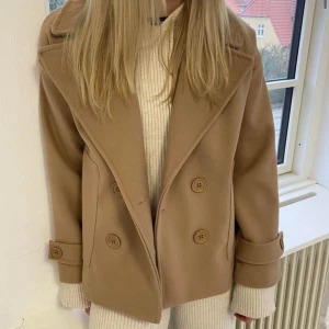 Beige kappa  - Säljer denna fina kappa från design by si då jag har flera i andra färger! Trendig och passar jättebra nu till hösten! Nypris 750 kr