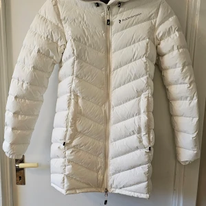PEAK PERFORMANCEFROST DOWN PARKA white - BESKRIVNING Den här dunjackan i glansigt material är en mysig vinterfavorit som är fodrad med premium 90/10-anddun för att hålla dig riktigt varm. Huva i Alaska-design ger extra skydd under kalla dagar