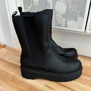 Svarta boots/låga stövlar/stövletter/ankelboots med platå sula. Endast använda en gång och som nya. I fusk läder som är enkelt att torka av när det blir smutsigt. I storlek 39. Kommer tyvärr inte till användning.