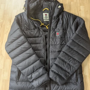 Fjällräven Herr jacka i strl L - Super fin tunnare dunjacka. Använd ett par gånger endast. Ser ut som ny.