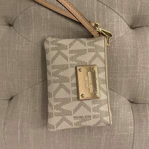 Säljer en snygg beige plånbok från Michael Kors med ett klassiskt MK-mönster. Den har en praktisk dragkedja och en stilren guldfärgad platta med logotypen på framsidan. Perfekt för att hålla ordning på kort och kontanter! Utmärkt skick 