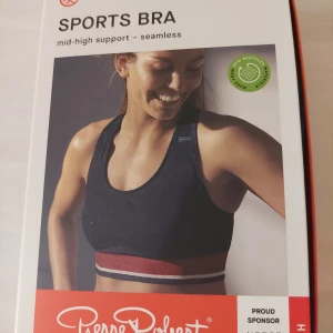 Svart sport-bh från Pierre Robert - En ny marinblå sport-bh från Pierre Robert i storlek M. Den har en sömlös design med medelhögt stöd, perfekt för träning. Materialet är en blandning av polyamid och återvunnen polyester, vilket gör den både bekväm och hållbar. 
