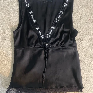Satin topp - Svart urringad topp med spets nertill Knappt använd och säljer på grund av att ja inte har haft tillfällen att använda den. I bra skick
