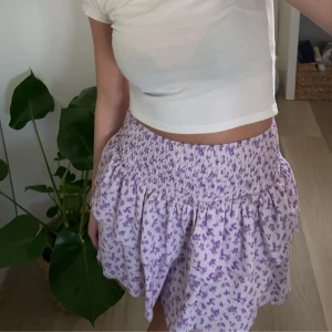 Lila blommig kjol från Gina Tricot - Säljer en superfin lila blommig kjol från Gina Tricot i storlek XS. Kjolen har en elastisk midja som gör den bekväm och lätt att bära. Perfekt för sommardagar eller en avslappnad vårlook. Materialet är mjukt och luftigt, vilket gör den idealisk för varmare väder.