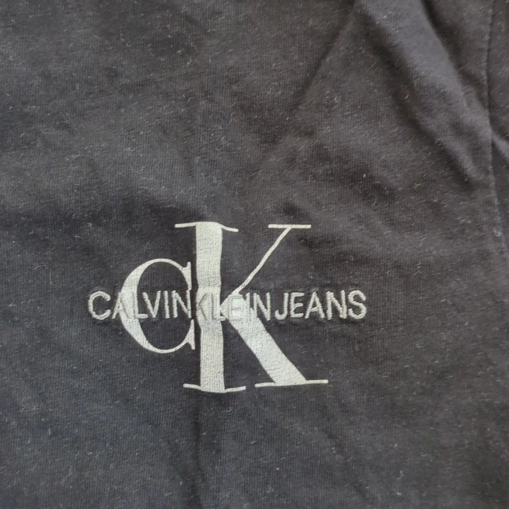 Säljer en stilren svart t-shirt från Calvin Klein Jeans. Den har en klassisk passform med korta ärmar och ett snyggt CK-logotryck på bröstet. Perfekt för en avslappnad och trendig look!. T-shirts.