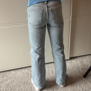 Ljusblå jeans med slitningar - Snygga ljusblå jeans med slitningar på knäna. De har en klassisk femficksdesign och en knappgylf. Perfekta för en avslappnad stil.