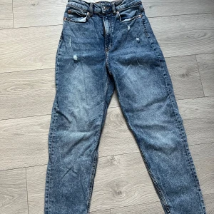 Jeans  - Snygga blå jeans med hög midja och klassisk femficksdesign. Jeansen har en straight passform och är perfekta för en avslappnad stil. De har en dragkedja och knapp framtill.