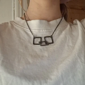 Svart halsband med geometriska former - Snyggt svart halsband med tre sammanlänkade geometriska former. Kedjan är tunn och justerbar, vilket gör det enkelt att anpassa längden. Perfekt för att ge en modern touch till din outfit.