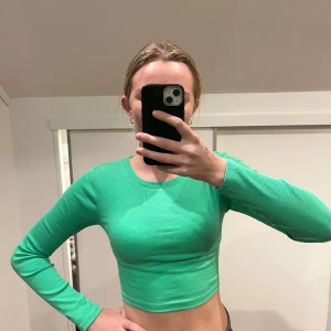 Grön ribbad topp med snörning - Snygg grön ribbad topp med långärmad design och cool snörning i ryggen. Perfekt för att ge en trendig touch till din outfit.