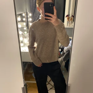 Beige stickad tröja från Thernlunds - Mysig beige stickad tröja från Thernlunds i storlek S. Tröjan är tillverkad av en mjuk blandning av alpacka, ull och syntetmaterial, vilket gör den perfekt för kyliga dagar. Den har långa ärmar och en klassisk rund halsringning.
