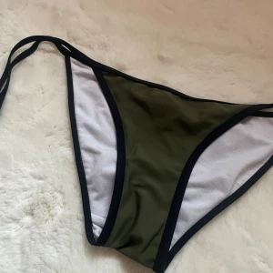 Olivgrön Bikiniunderdel  - Hejj! Säljer denna supersöta bikiniunderdelen i en jättefin olivgrön färg. Den är aldrig använd, alltså i nyskick och har därav inga defekter. Färgen på bikinin gör att man ser otroligt brun och fräsch ut under sommaren!🤩Om du skulle ha några frågor är det bara att höra av dig!
