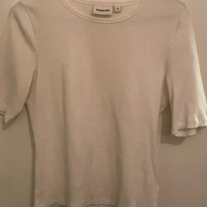 Vit ribbad topp från Kappahl - Säljer en stilren vit ribbad topp från Kappahl. Toppen har korta ärmar och en rund halsringning, perfekt för en enkel och snygg look. Oanvänd