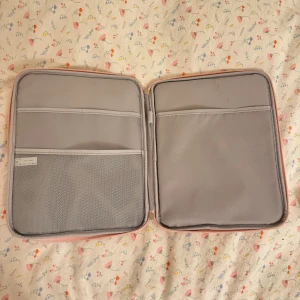 Rosa datorväska med dragkedja - Säljer en praktisk rosa datorväska med dragkedja. Väskan har flera fack inuti för enkel organisering och en stilren design. Perfekt för att hålla din laptop och tillbehör säkra och organiserade.