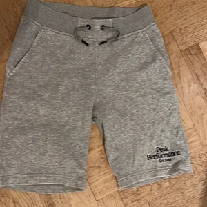 Grå shorts från Peak Performance - Snygga grå shorts från Peak Performance med broderad logga på benet. De har en bekväm passform med snörning i midjan och är perfekta för en avslappnad stil. Tillverkade i mjukt material för extra komfort. Pris kan diskuteras!