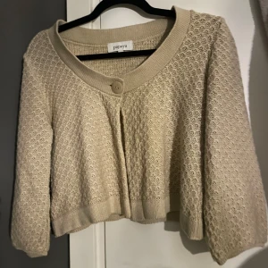 Beige kofta från Papaya - Säljer en söt beige kofta från Papaya med ett fint stickat mönster. Koftan har trekvartsärmar och en knapp framtill. En perfekt bolero