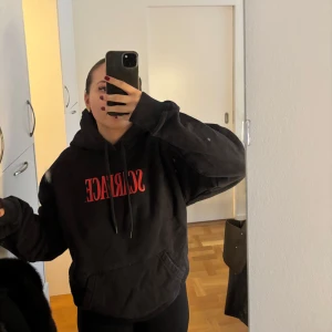 Svart Scarface hoodie - Säljer denna svarta hoodie med röd Scarface-text på framsidan och ett stort tryck av Tony Montana på baksidan. Perfekt för dig som vill ha en statement piece i garderoben. Hoodien har en klassisk passform med känguruficka och justerbar huva.