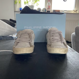 Vita sneakers från Philippe Model - Snygga vita sneakers från Philippe Model med klassisk design och snörning. Skorna har en diskret logga på sidan och är perfekta för en avslappnad stil. Obs väldigt användna. Kom gärna med pris förslag 