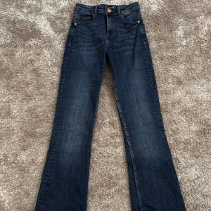 bootcut jeans - Snygga mörkblå jeans med bootcut-stil. De har klassiska fem fickor och en knappgylf. Perfekta för en avslappnad look med en touch av retro. Använda ca 5 gånger så i nyskick. Nypris ca 250. Priset är förhandlingsbart. Hör av er för frågor eller fler bilder ❤️