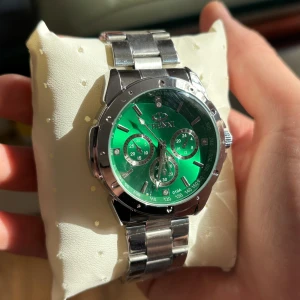 Silverfärgad klocka med grön urtavla - Helt ny, Snygg klocka från Chenxi med grön urtavla och silverfärgad länkarmband. Klockan har flera små urtavlor och en stilren design som passar perfekt för den som vill sticka ut. Perfekt accessoar för att lyfta din stil. Nypris från Chenxi 649kr