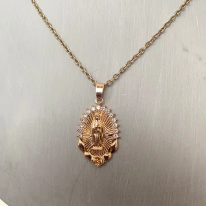 Guldhalsband med  medaljong - Elegant guldhalsband med en detaljrik medaljong Medaljongen är omgiven av gnistrande stenar som ger en lyxig känsla. Perfekt för att ge en personlig touch till din stil. Okänd metall 