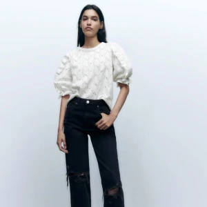 Vit blus med volangärmar - Säljer en söt vit blus med puffiga volangärmar och ett diskret hålmönster. Perfekt för en stilren look. Blusen har en rund hals och är tillverkad i ett lätt material.