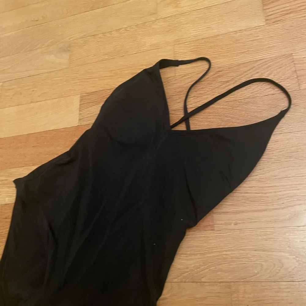 Snygg svart baddräkt med smala axelband som korsas i ryggen. Den har en v-ringad design. Perfekt för en stilren look på stranden eller vid poolen. Banden är även avtagbara, så man kan välja om man vill korsa dem eller inte (kolla sista bilden). ALDRIG ANVÄND.💕 Står ingen storlek men skulle säga XXS-S.. Sportswear.