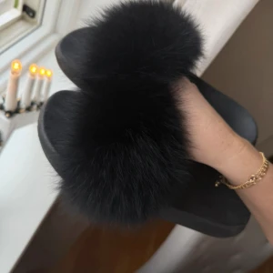 Svarta tofflor med pälsdetalj - Säljer ett par svarta tofflor med mjuk pälsdetalj på ovansidan. Perfekta för att hålla fötterna varma och bekväma hemma. Sulan har ett mönster för bättre grepp. Nyskick. Stl 40. 