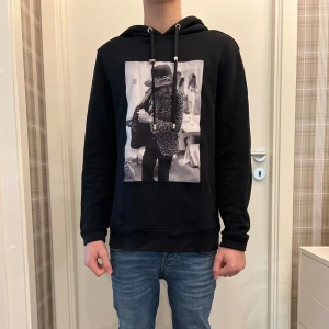 Svart hoodie från Limitato - Säljer en svart hoodie från Limitato med Jimmy Hendrix tryckt på framsidan. Tröjan är tillverkad i 100% bomull och har en bekväm passform med långa ärmar och justerbar huva. Perfekt för en avslappnad stil. Nypris på denna hoodie är runt 4k. Det är en storlek M och modellen på bilden är 170 cm. Vid snabb affär kan priset diskuteras