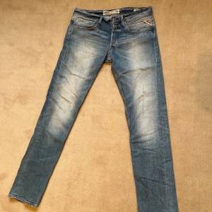 Blå jeans från Replay. Dm för fler bilder  - Snygga blå jeans från Replay med en klassisk femficksdesign och knappgylf. De har en lätt tvättad look och är perfekta för en avslappnad stil. Märkeslappen i läder baktill ger en extra touch av kvalitet. Jeansen är unika och varsamt använda. Säljes för hälften av originalpriset.