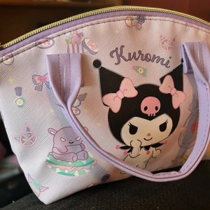 Söt liten väska med Kuromi-motiv! - Söt liten väska med handtag, justerbar axelrem och dragkedja med Kuromi-motiv. Mått: 25 x 20 cm. Ny och oanvänd. 