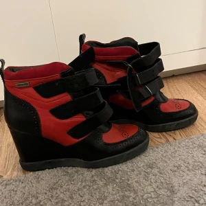 Svart och röd klacksko - Snygga kilklacksskor i svart och rött med dekorativa detaljer och kardborreband. Liknar Isabel marant skor! Perfekta för att ge lite extra höjd och stil till din outfit. 
