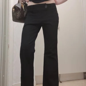 Svarta kostymbyxor med låg midja - Snygga svarta kostymbyxor med låg midja och bootcut-stil. Byxorna har en stilren design med knappar framtill och passar perfekt för en chic look. Byxorna har extra långa ben och är lite långa på mig som är 173! 1400💕💕