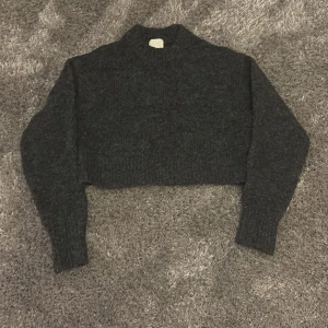 Mörkgrå stickad tröja från H&M - Säljer en mörkgrå stickad tröja från H&M. Tröjan är stickad och har långa ärmar med ribbade muddar. Perfekt för kyligare dagar.