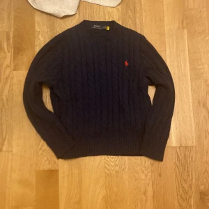 Mörkblå stickad tröja från Polo Ralph Lauren - Säljer en snygg mörkblå stickad tröja från Polo Ralph Lauren. Storlek M men är lite liten så passar S mycket bra också.