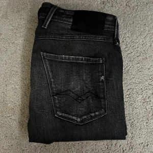 Svarta jeans från Replay - Snygga svarta jeans från Replay med en cool sliten look. De har klassiska fem fickor och en bekväm passform. Perfekta för en avslappnad stil. Hör av dig vid funderingar eller frågor 