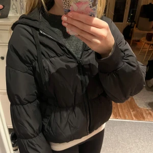 Svart pufferjacka från h&m - Säljer en svart pufferjacka från H&M. Jackan har en dragkedja framtill och en mysig huva. Perfekt för kyliga dagar med sin vadderade design. Enkel och stilren look som passar till det mesta. 