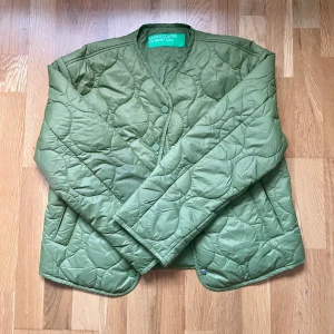 Grön quiltad jacka från United Colors of Benetton - Säljer en snygg grön quiltad jacka från United Colors of Benetton. Jackan har en stilren design med knappar framtill och långa ärmar. Perfekt för att hålla värmen under kyliga dagar. Priset kan självklart diskuteras vid snabb affär! ⭐️💨