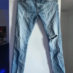 Blå jeans från Diesel - Säljer ett par blå Diesel jeans, modell Thommer. De har en snygg slitning på ena benet och klassisk femficksdesign. Perfekta för en avslappnad stil.