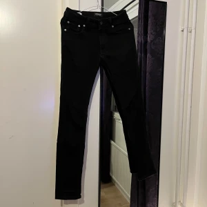 Svarta jeansbyxor - Snygga svarta jeansbyxor med skinny passform och midwaist. Perfekta för en stilren look. Byxorna har klassisk design med knappar och dragkedja framtill.