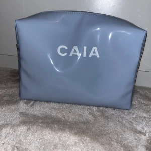 Blå necessär från CAIA - Snygg och praktisk blå necessär från CAIA med dragkedja. Perfekt för att förvara smink eller andra småsaker. Enkel och stilren design.