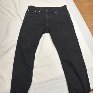 Svarta Levis 502 jeans - Snygga svarta Levis 502 jeans med klassisk design. De har en dragkedja och knappar framtill samt fem fickor. Perfekta för en stilren look.