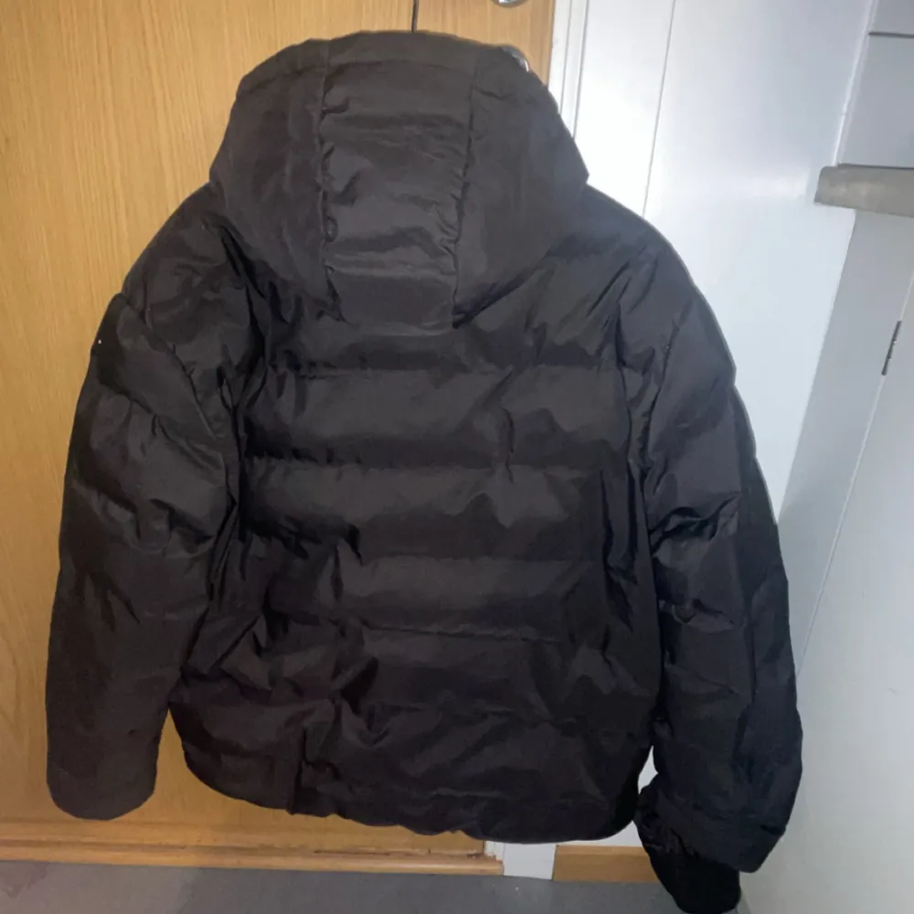 Säljer en svart pufferjacka med huva. Jackan är vindtät och vattenavvisande, perfekt för kyliga dagar. Den har en dragkedja framtill och är långärmad. Passar bra för både höst och vinter. Nästan helt ny. Takit.