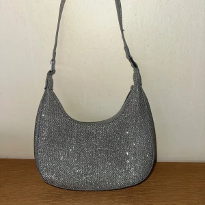 Glittrig axelväska - Snygg axelväska i glittrigt silvermaterial. Perfekt för att ge din outfit något litet extra!🩶